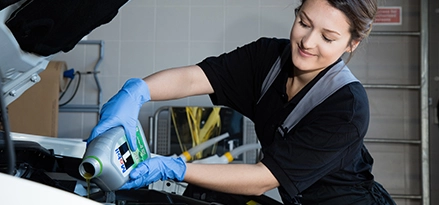 een persoon die mobil 1 olie bijvult in de auto